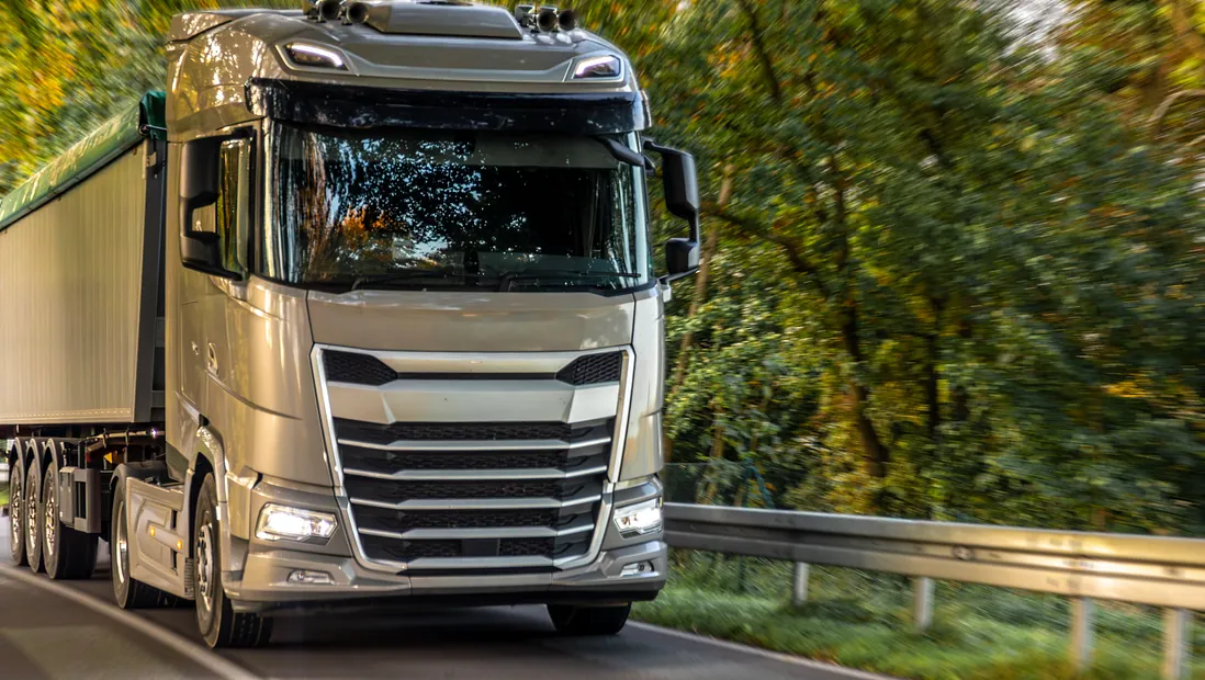 silverfärgad lastbil kör på landsväg