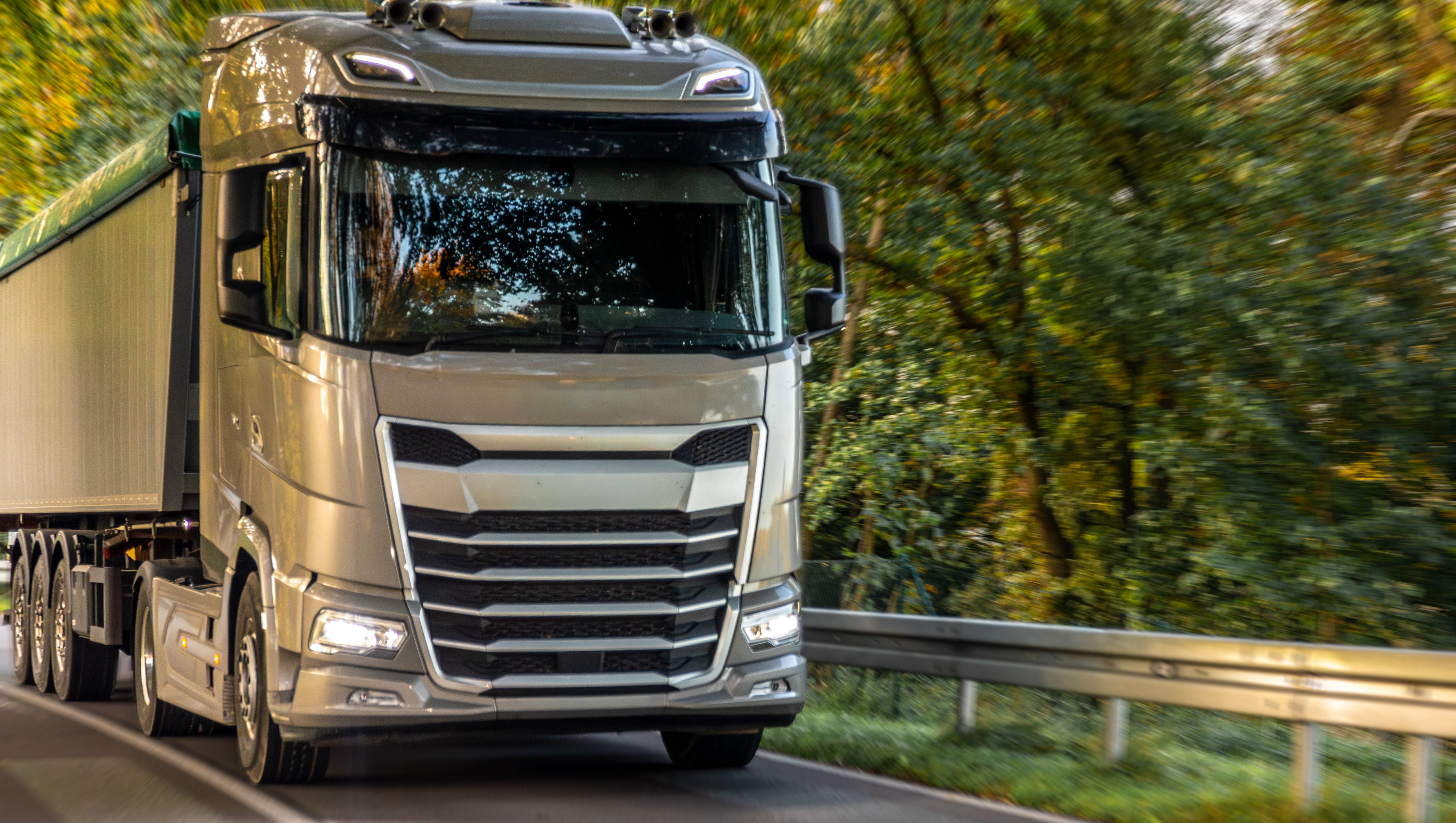 silverfärgad lastbil kör på landsväg