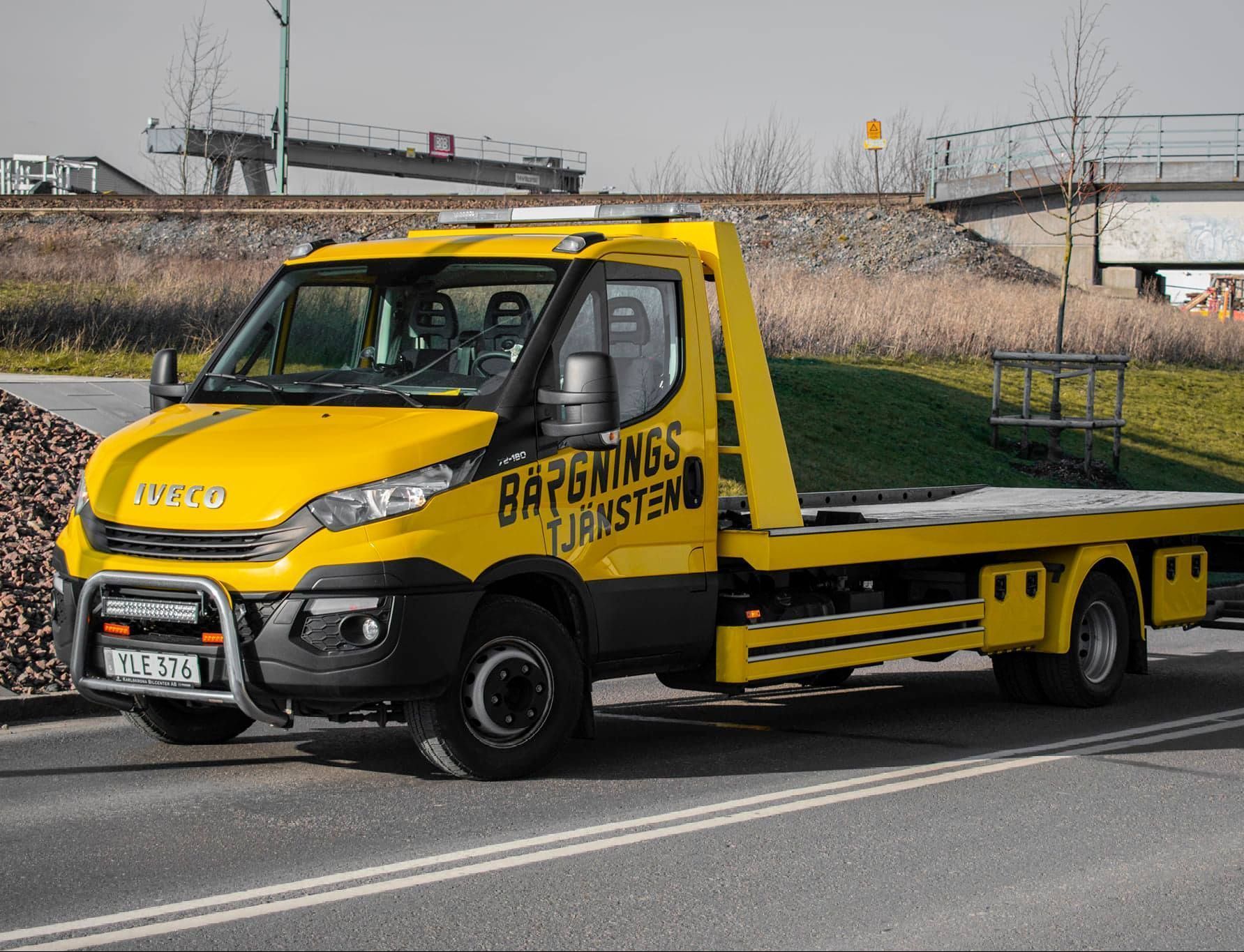 Gul liten bärgningslastbil på en väg