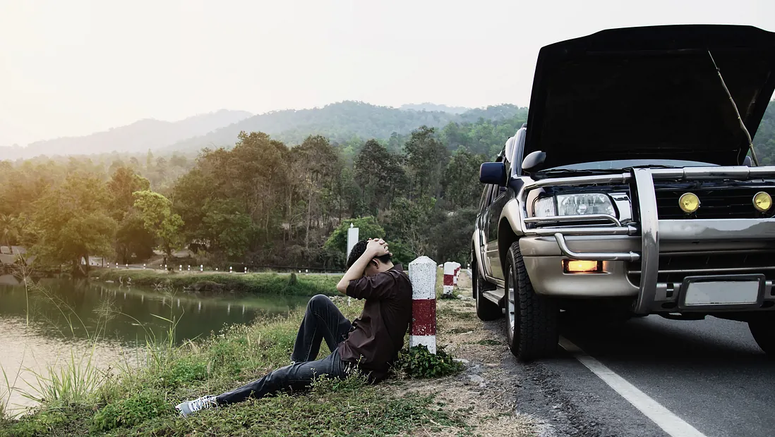 man vid vägkanten med trasig bil