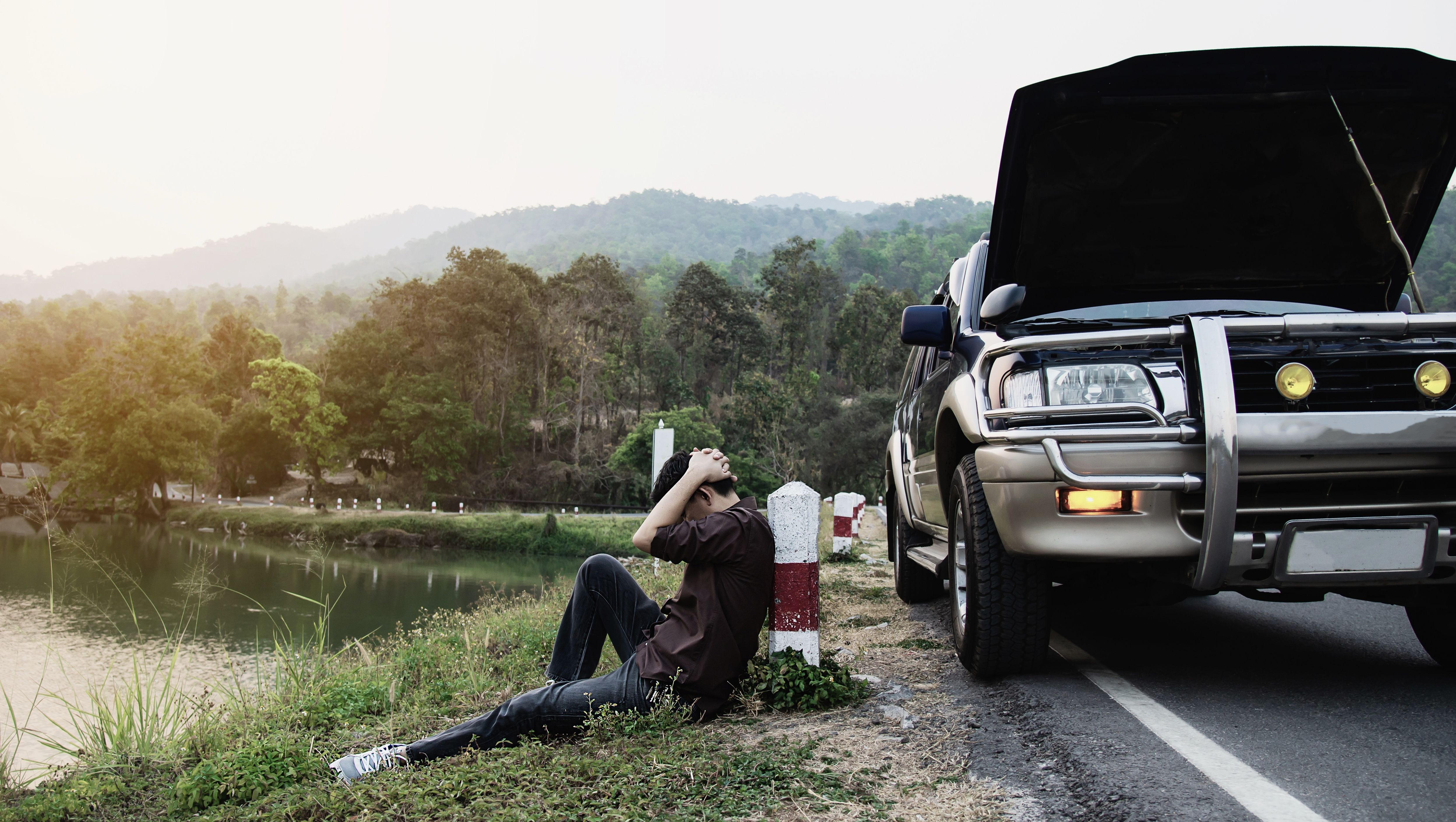 man vid vägkanten med trasig bil